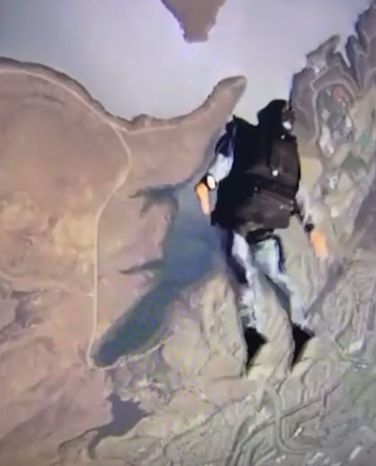 HALO jumper descending over desert terrain at altitude